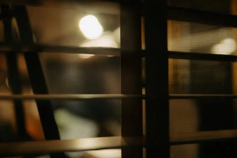 Warm Cinematic Desk Setup Viewed Through Window Blinds at Night Stock Photos