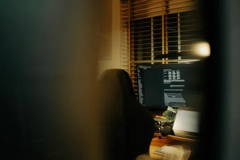 Warm Cinematic Desk Setup Viewed Through Window Blinds at Night Stock Photos