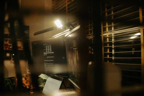Warm Cinematic Desk Setup Viewed Through Window Blinds at Night Stock Photos