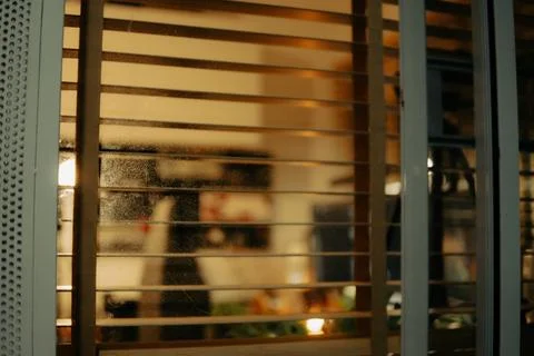 Warm Cinematic Desk Setup Viewed Through Window Blinds at Night Stock Photos