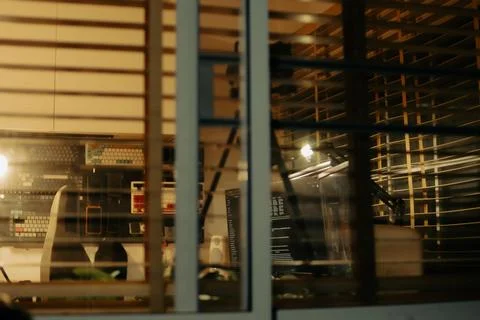 Warm Cinematic Desk Setup Viewed Through Window Blinds at Night Stock Photos