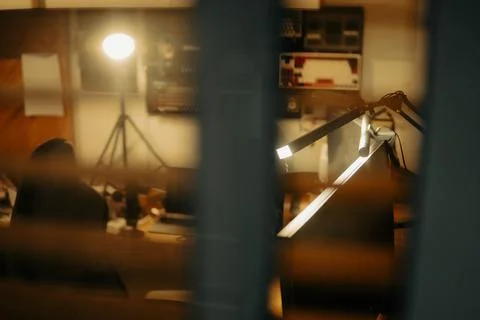 Warm Cinematic Desk Setup Viewed Through Window Blinds at Night Stock Photos
