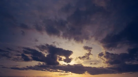 Warm cloudscape in timelapse. Dark purple clouds floating in a warm sunset. Stock Footage 87234584