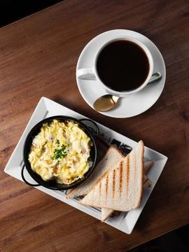 Warm coffee and fluffy eggs on rustic wooden table Stock Photos