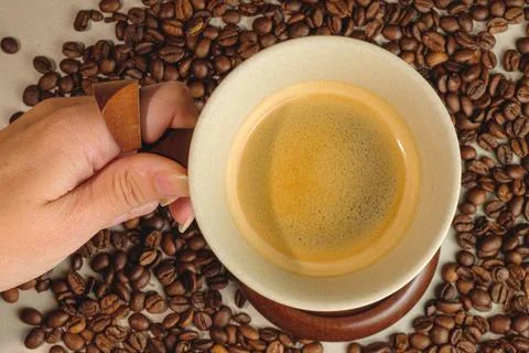 Warm coffee in a cozy setting surrounded by roasted beans Stock Photos