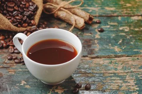 Warm coffee cup with roasted beans on rustic table Stock Photos