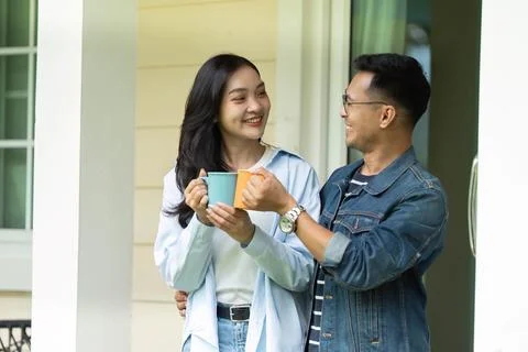 Warm connection. Young couple sharing smiles and drinks on the porch. Fotos Stock