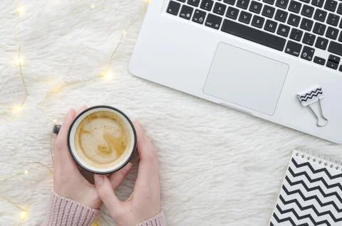Warm cozy winter workspace background. Flat lay. Girl holding a cup of coffee on Stock Photos
