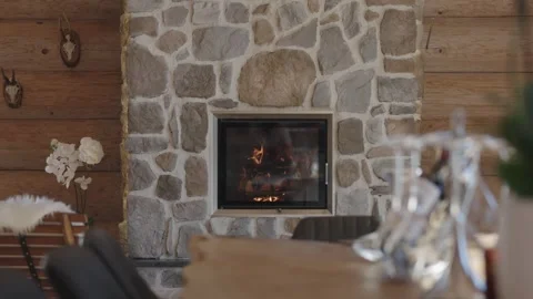 Warm, crackling fire burning in a stone fireplace inside a rustic wooden chalet Stock-Footage 335757241