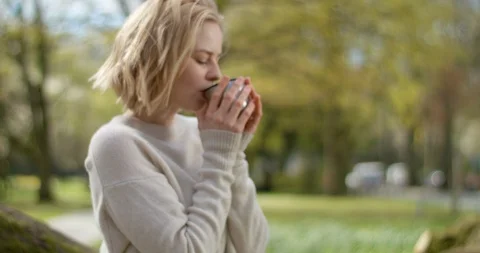 Warm cup of tea on a chilling spring morning warms female Video stock 106946617