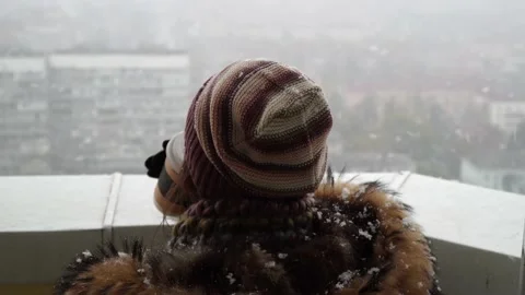 A warm-dressed girl drinks coffee and looks at the falling snow. Stock Footage 143661906
