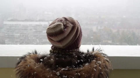 A warm-dressed girl drinks coffee and looks at the falling snow. Stock Footage 143772651