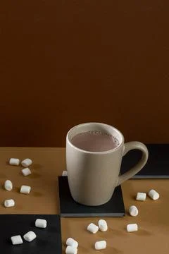 Warm drink in a cup with marshmallows on a table with brown and black color.. Stock Photos