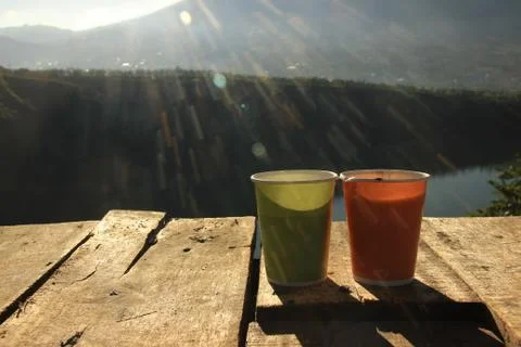 A warm drink on a wooden table against a scenic backdrop and flares of sunshi Stock Photos