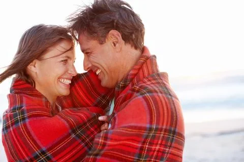 Warm embrace. A devoted and affectionate couple wrapped in a blanket on the Stock Photos