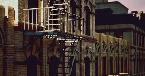 Warm evening light casts shadows on a fire escape attached to a brick buildin Ilustración de archivo