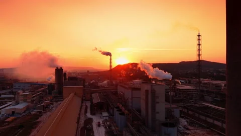 Warm evening light covers the rooftops, pipelines, and surrounding factory Stock Footage 345614928