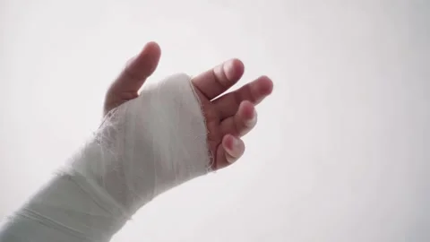 Warm up the fingers of the young man's broken arm close-up against a white Stock-Footage 132996350
