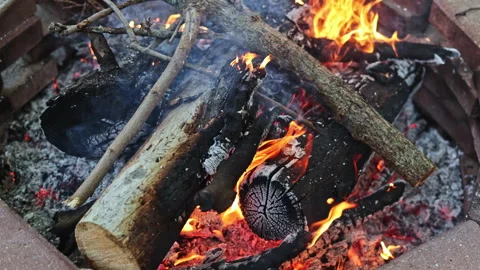 Warm fire burns brightly in a fire pit surrounded by stones in the evening Stock Footage 337908340