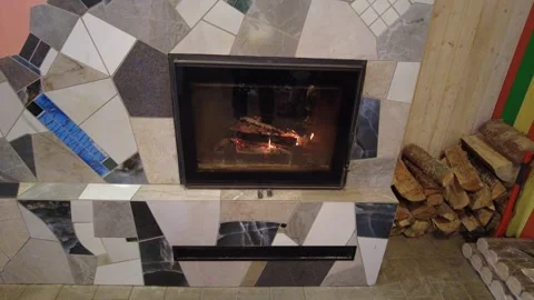 Warm fire in a cozy room with stone wall and logs stacked nearby for winter nigh Stock-Footage 332452910