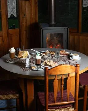 Warm fireplace glows behind rustic dining table Stock Photos