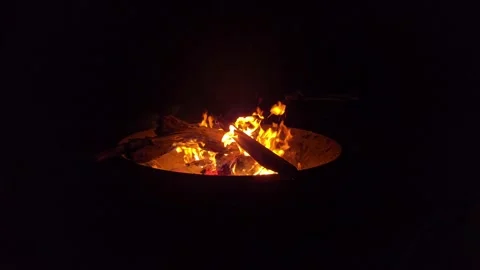 Warm flames dance in a cozy outdoor setting during a relaxing night gathering Stock Footage 296498516