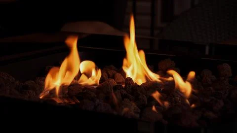 Warm Flames Dancing At Night In A Fire Pit With Lava Rocks for Cozy Outdoor Stock Photos