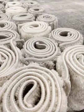 Warm fluffy carpets in light and gray tones rolled into large rolls in a hy.. Stock Photos