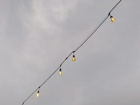 Warm Glow of Outdoor String Lights Against a Cloudy Evening Sky Stock Photos
