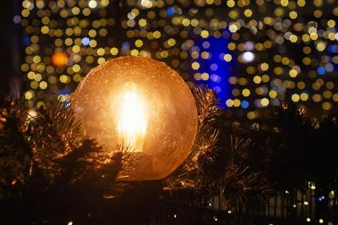 Warm glowing light bulb surrounded by Christmas garland with colorful bokeh.. Foto stock