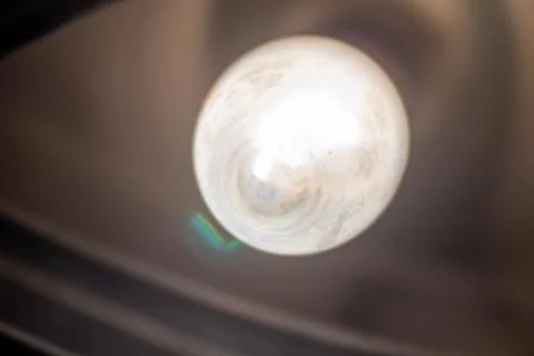 Warm glowing lightbulb hanging from the ceiling in a dark room interior Fotos Stock