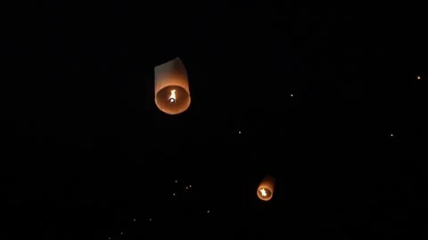 Warm glowing paper sky lantern rising at night with visible flame inside Video stock 346142102