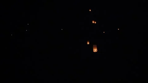 Warm glowing paper sky lantern rising at night with visible flame inside Video stock 346142569