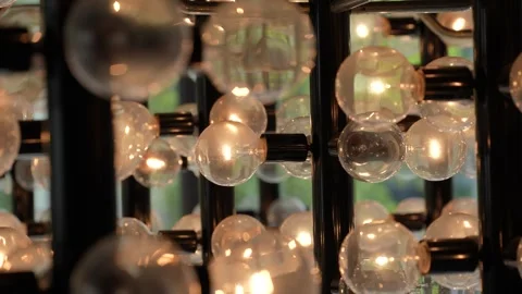 Warm glowing round light bulbs on black metal grid with bokeh Stock Footage 346363542