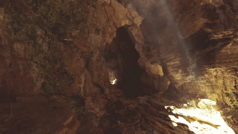 Warm gold rays illuminate rugged cave ceiling and dust particles Stockbeeldmateriaal 329941487