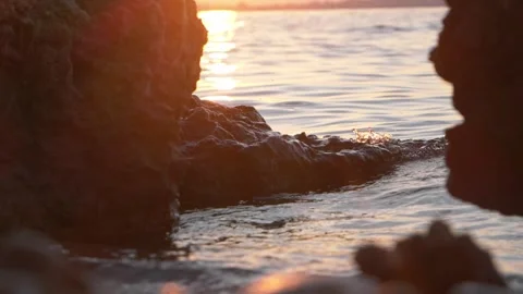 Warm golden sunset glowing brightly between dark rocky coastal shores Stock Footage 337409346