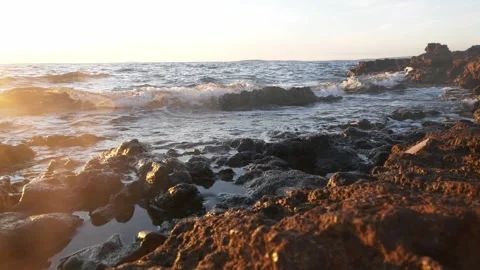 Warm golden sunset light glowing over ocean coastal rocky waves Stock Footage 337409310