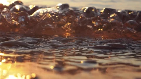 Warm golden sunset light shimmers across tiny sparkling water bubbles Stock Footage 337409129