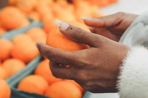 Warm hands gently hold a bright orange Foto stock