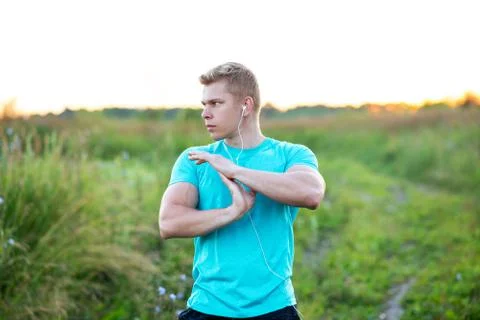 Warm-up hands, a young guy runner early in the morning doing the headphones. A Stock Photos