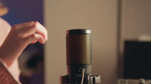 Warm home studio close view of condenser microphone with hand moving near grille Stock Footage 343541985
