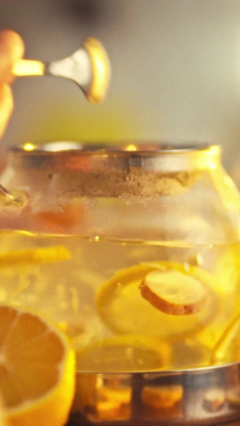In a warm kitchen a man crafts a tea blend by gently stirring sliced lemons Stock Footage 334398553