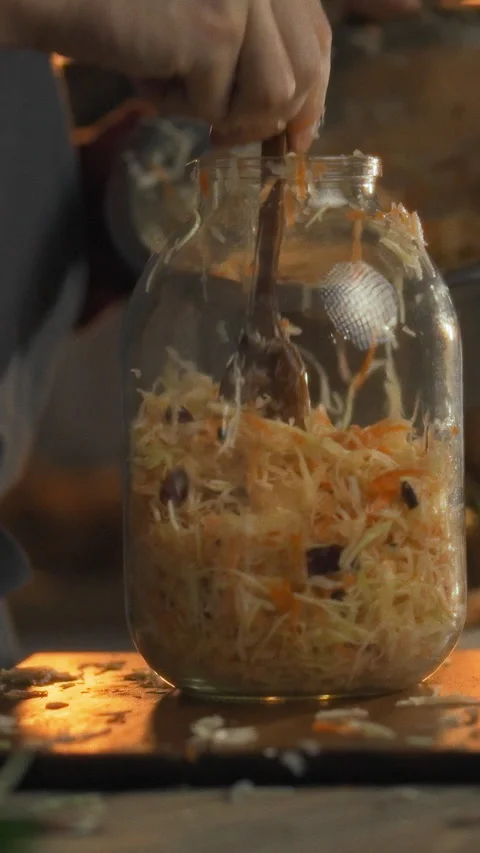 In warm kitchen person layers crisp cabbage and shredded carrots into a jar Stock Footage 334395598