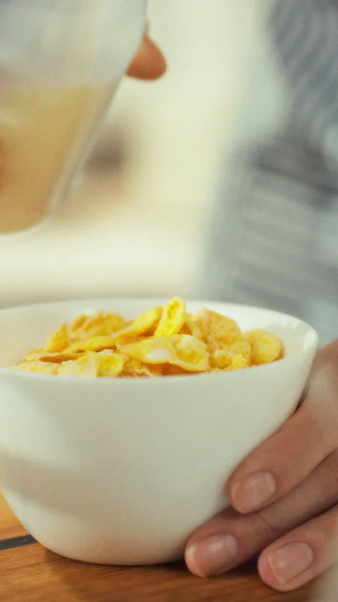 In a warm kitchen a person prepares breakfast by pouring cold milk into a bo Stock Footage 331600818
