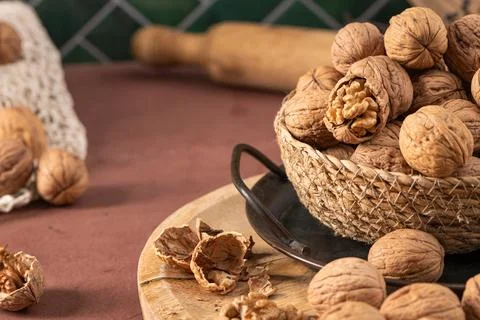 A warm kitchen scene featuring a woven basket overflowing with walnuts on a.. Stock Photos
