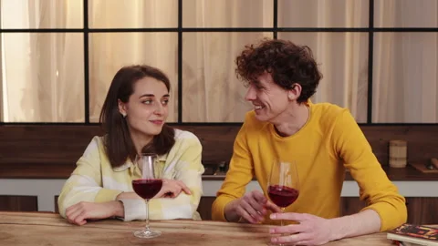 In a warm kitchen setting, a cheerful couple happily savors wine in each others Stock Footage 278340896