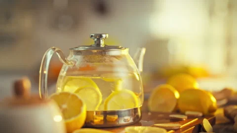In a warm kitchen setting a transparent glass teapot filled with swirling le Stock Footage 331353241