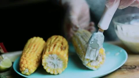 Warm kitchen study: serving grilled corn on a blue plate Stock Photos