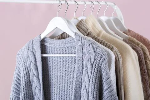 Warm knitted clothes hanging on a rack Stock Photos