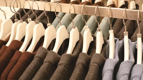 Warm knitted sweaters hang on white hangers in clothing store. Stock Footage 289262075